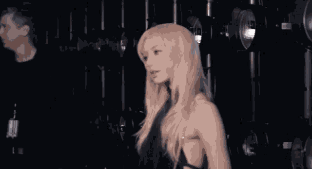 a woman with blonde hair is standing in front of a bunch of lights .
