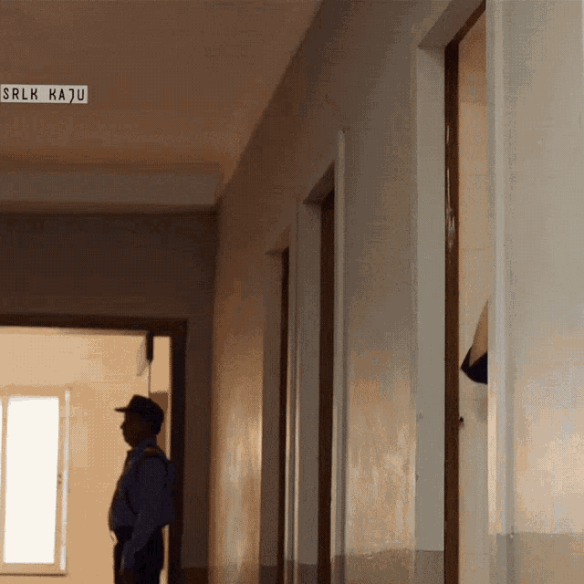 a man stands in a hallway with a sign above him that says srlk maju