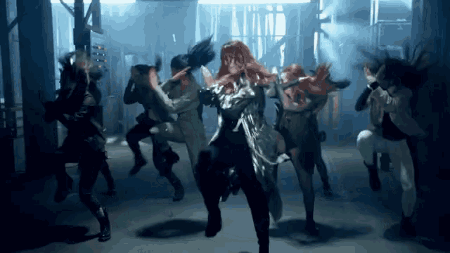a group of people are dancing in a dark room with a woman in the middle