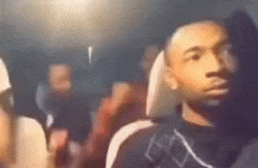 a man is sitting in the back seat of a car with a group of people behind him .