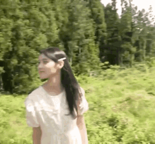 a woman in a white dress is standing in a field .