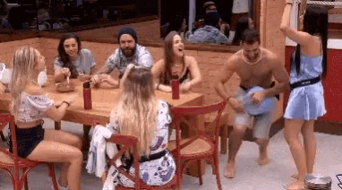 a group of people are sitting at a table while a woman is dancing in front of them .