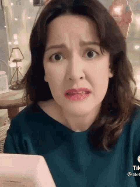 a woman is making a funny face while looking at herself in a mirror .