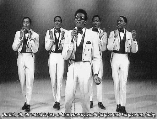 a group of men in tuxedos are singing into microphones .