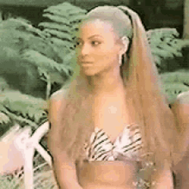 a woman with long hair is wearing a zebra print bikini top and ponytail .