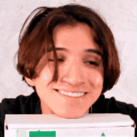 a young man is smiling while holding a pizza box .