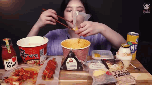 a woman is eating a bowl of noodles with chopsticks while a bottle of fanta sits on a table