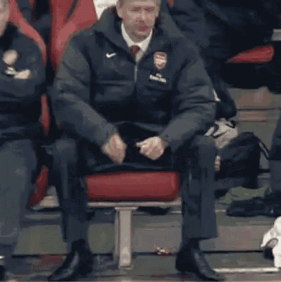a man in an arsenal jacket is drinking from a bottle .