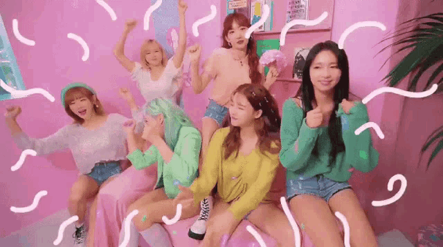 a group of girls are sitting on a bed with their hands in the air