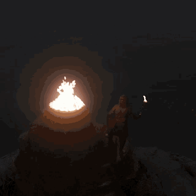 a person holding a torch standing in front of a fire