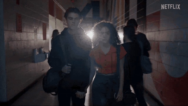 a couple of people walking down a hallway with a netflix logo in the background