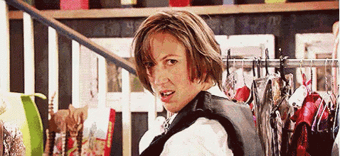 a woman is standing in front of a rack of clothes and looking back at the camera .