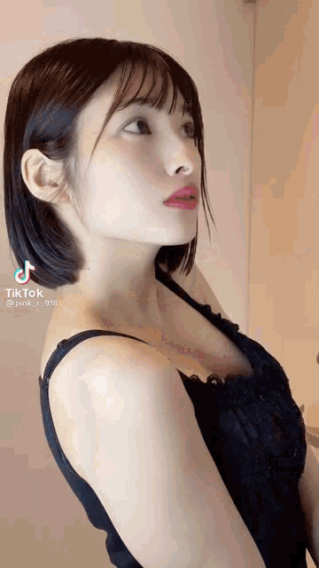 a woman with short hair is wearing a black tank top and looking up .