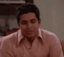 a man in a pink shirt is laughing and smiling .