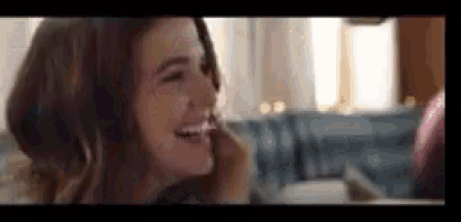 a woman is laughing in front of a mirror while applying makeup .