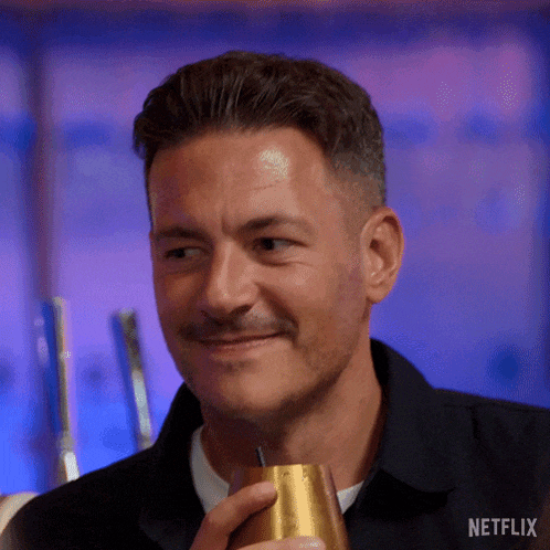 a man is holding a gold cup with a straw in his hand and smiling .