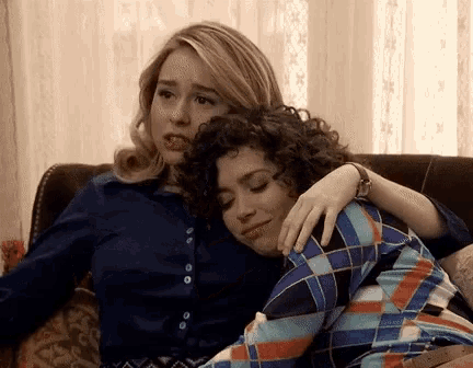 two women are hugging each other while sitting on a couch .