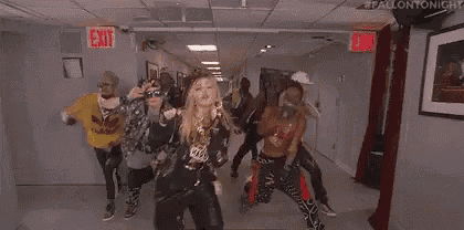 a group of people are dancing in a hallway in front of a red exit sign .