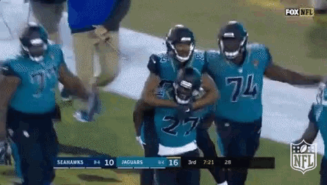 a group of seahawks and jaguars players are walking on the field .