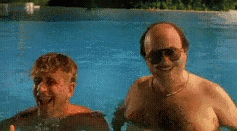 two men are swimming in a swimming pool without shirts .