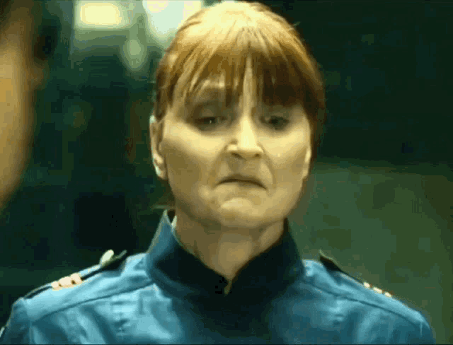 a woman with red hair is wearing a blue uniform with a badge on the shoulder