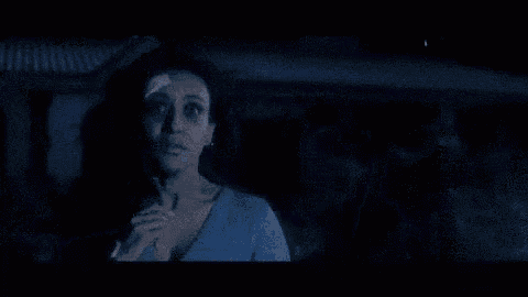 a woman in a blue dress is standing next to a man in a blue shirt in the dark .
