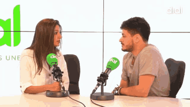 a man and a woman are sitting in front of microphones that say dial on them