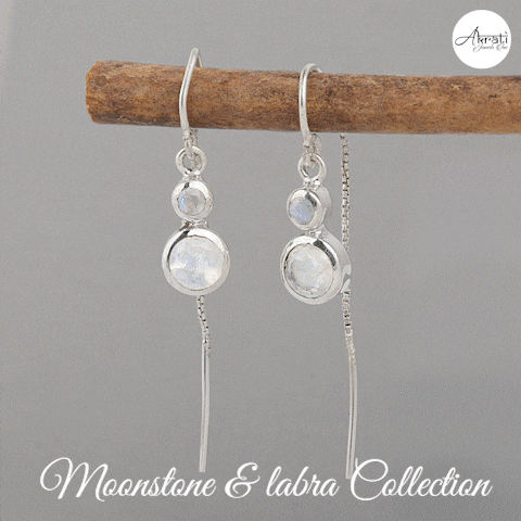 a pair of moonstone and labra earrings are hanging on a stick