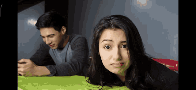 a man and a woman are sitting at a table with the woman making a sad face