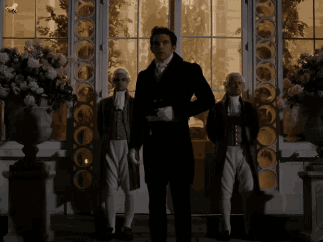 a man in a suit stands in front of a window