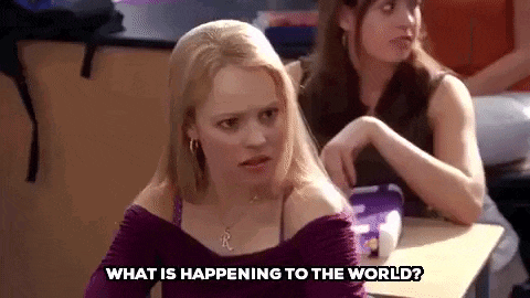 a woman is sitting at a desk in a classroom and talking to another woman .