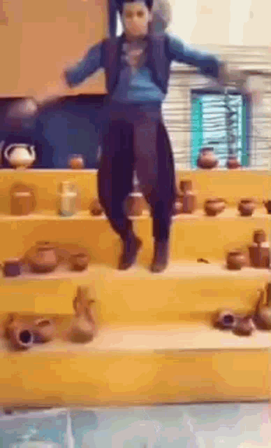 a boy is dancing on a set of stairs in front of a display of pottery .