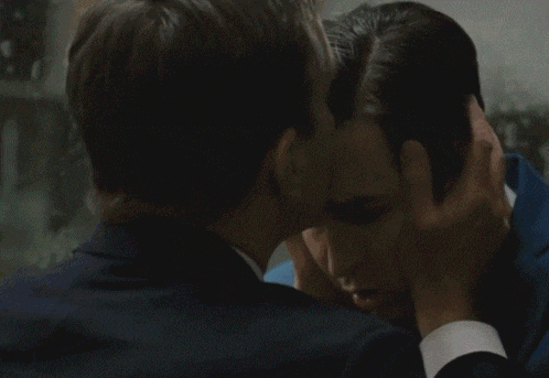 two men are touching each other 's faces and one has his hand on the other 's ear