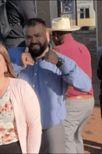 a man with a beard is giving a thumbs up while wearing a cowboy hat