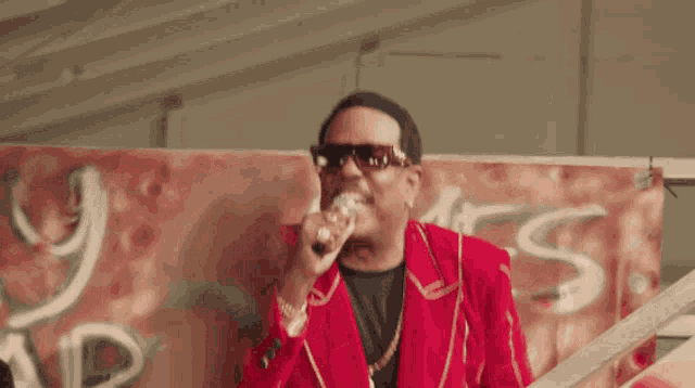 a man in a red jacket is singing into a microphone in front of a sign that says rt