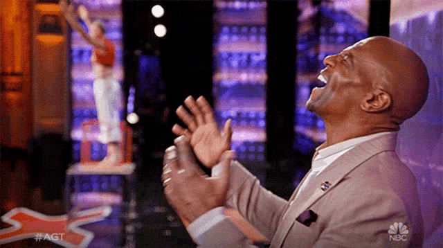a man in a suit is clapping in front of a basketball player on nbc