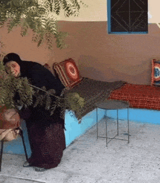a woman in a hijab is standing in front of a couch .