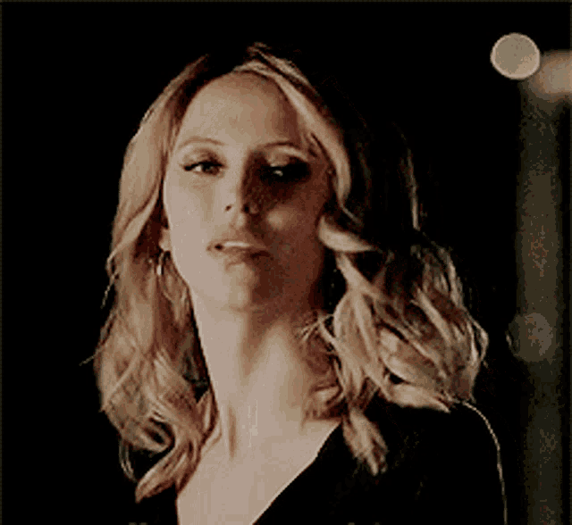 a woman with blonde hair and a black shirt is looking at the camera