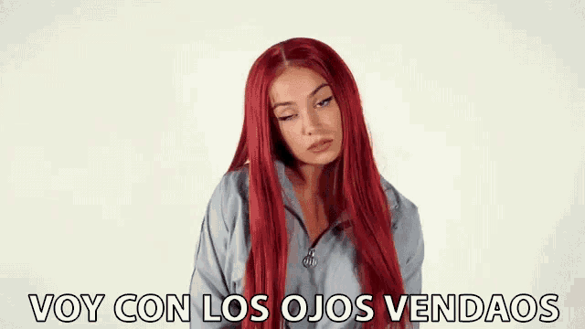 a woman with long red hair is wearing a gray jacket and says voy con los ojos vendaos .