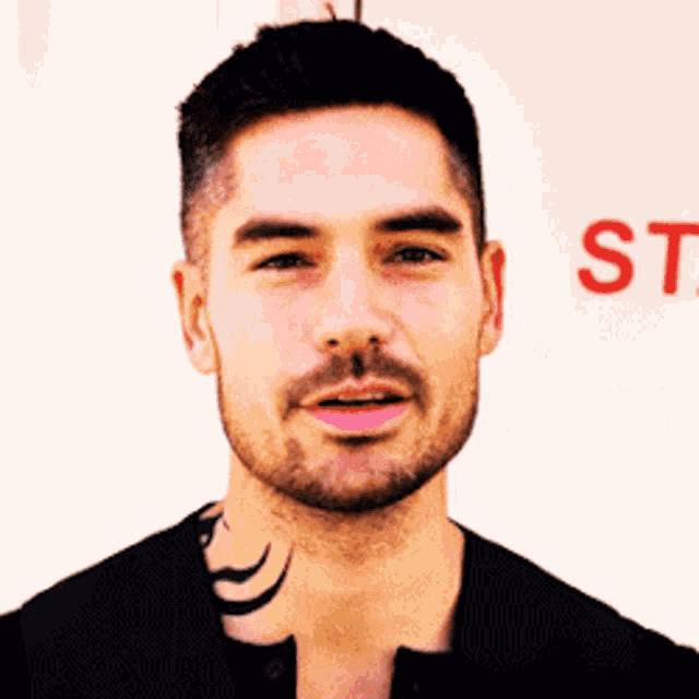 a man with a tattoo on his neck is standing in front of a sign that says st.