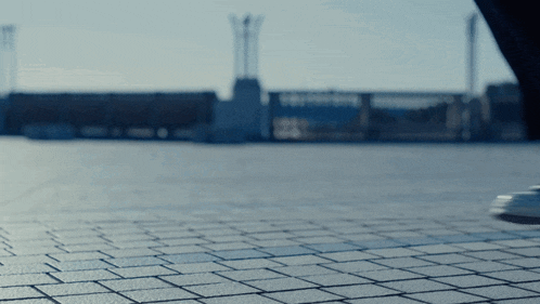 a person is walking on a brick sidewalk in front of a city