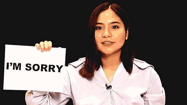 a woman holds a sign that says i 'm sorry