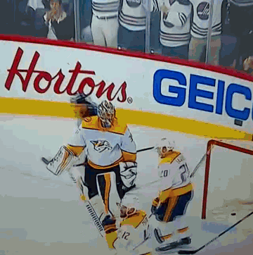 a hockey game is being played in front of a sign that says hortons geico