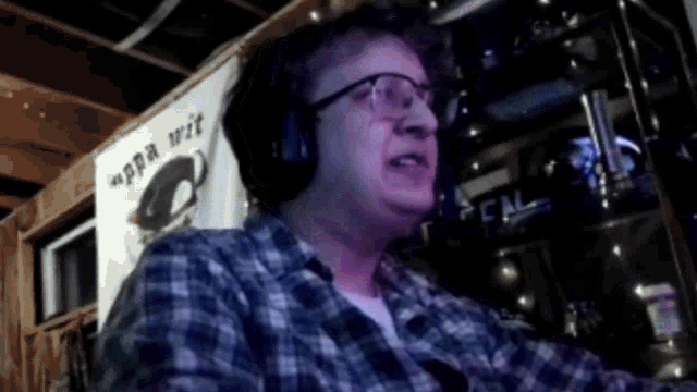 a man wearing glasses and headphones is sitting in front of a sign that says ' ppa wit ' on it