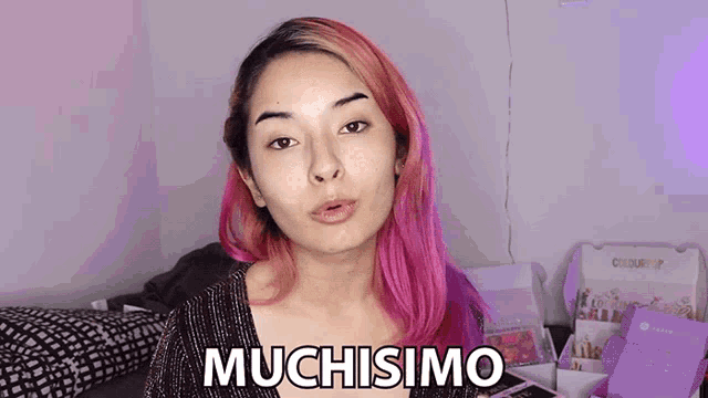 a woman with pink hair says muchisimo in front of a box