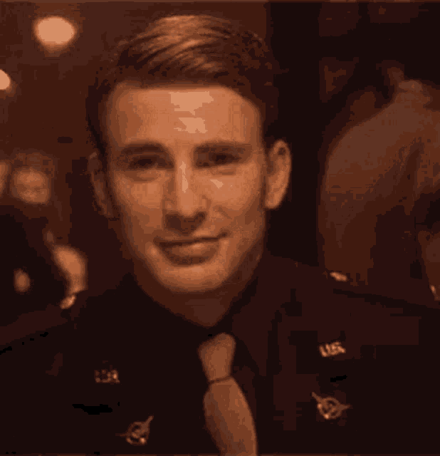 a man in a military uniform and tie is smiling and looking at the camera .