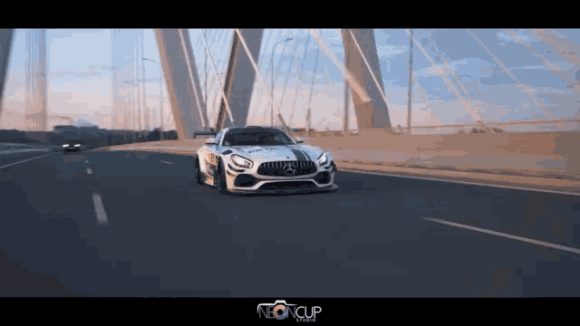 a white mercedes is driving on a highway next to a neoncup studio sign