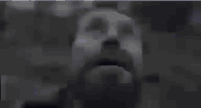 a man with a beard is standing in the dark with his eyes closed and his mouth open .
