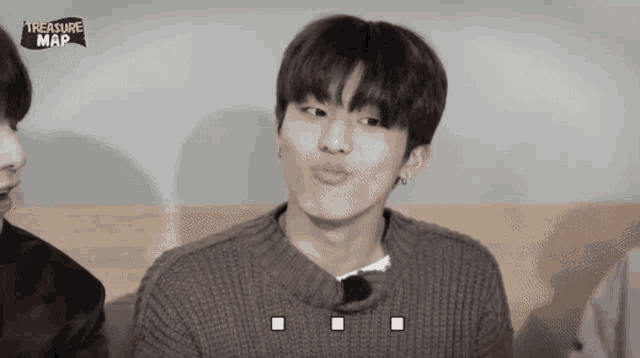 a young man making a funny face in front of a treasure map logo