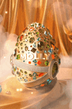 a gold egg with molly written on it is sitting on a table